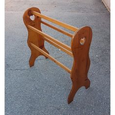 a wooden bench sitting on the side of a road next to a parking lot with no one around it