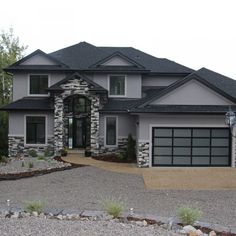 a large gray house with two garages on the front and one car door open