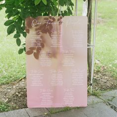 a pink wedding seating plan hanging from a tree