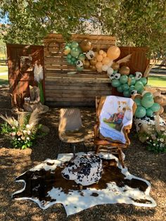 a cowhide rug and chair in front of a wooden fence with balloons on it