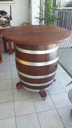 a large wooden barrel sitting on top of a tile floor next to a potted plant