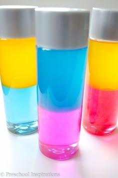 three glasses filled with colored liquid sitting on top of a white table next to each other