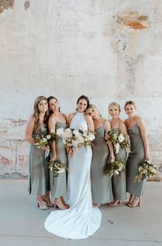 a group of women standing next to each other wearing dresses and holding bouquets in their hands