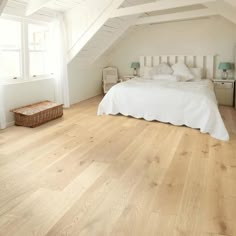 an attic bedroom with white walls and wood flooring on the ceiling, along with a bed