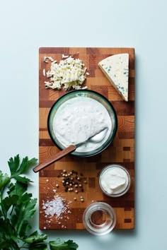 a wooden cutting board topped with cheese and dip