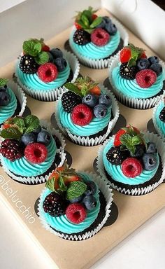 cupcakes with blue frosting and fresh berries on top