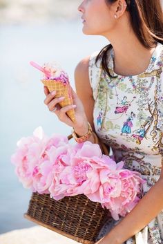 a woman holding an ice cream cone and pink flowers