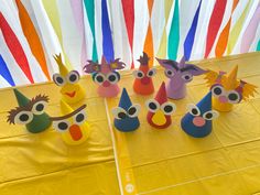 some paper birds are on a table with colorful streamers in the background and one bird is wearing a party hat