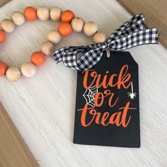 a wooden bead necklace with an orange and black trick or treat tag on it