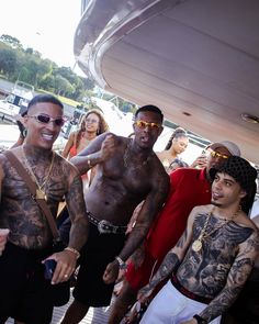 two men with tattoos on their arms and chest standing next to each other in front of a group of people