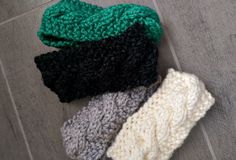 three knitted hats laying on the floor next to each other, one black and one green