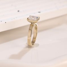 a yellow gold ring with a single diamond on it's side, sitting on a white surface