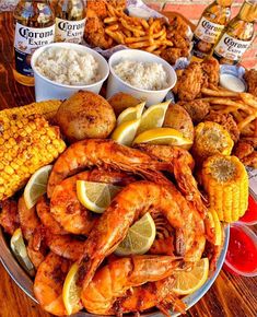 shrimp, corn on the cob, and other food items are arranged on a platter