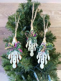 three ornaments hanging from a christmas tree on top of a wooden table next to scissors