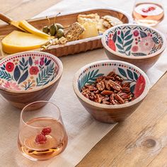 three bowls with pecans in them sitting on a table next to some fruit and cheese