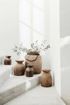 some vases sitting on the steps in front of a window with an olive branch