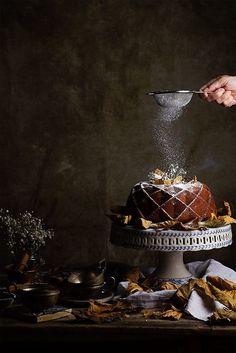 a person is sprinkling sugar on a cake