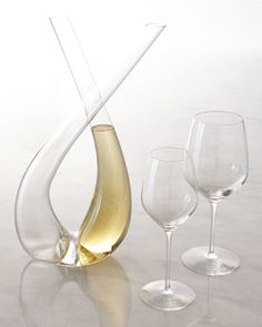 three wine glasses and a vase on a white table with an upside down glass in the middle