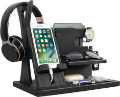 a cell phone and headphones are on a stand with earbuds, books, and other items