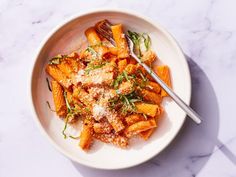 a white bowl filled with pasta covered in sauce and parmesan cheese next to a fork