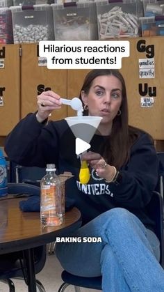 a woman sitting at a table with a spoon in her hand and an ad on the wall behind her