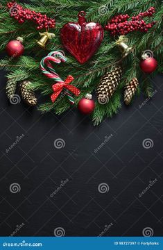 christmas decorations on a black background with pine cones, candy canes and baubles