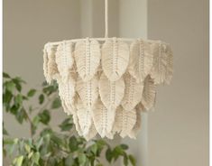 a white chandelier hanging from a ceiling next to a potted plant