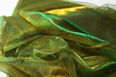 green and gold ribbon on top of each other in close up view with white background