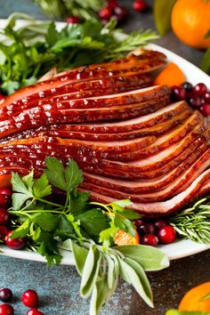 sliced ham on a platter with cranberries, oranges and herbs for garnish