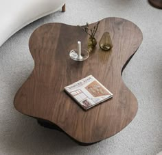 a wooden table sitting on top of a carpeted floor next to a white couch