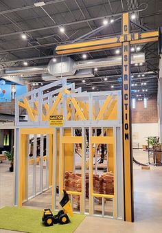 a yellow and gray building with a crane on the ceiling in an indoor area that looks like a construction site