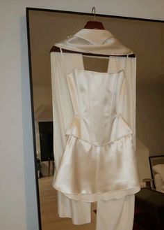 a white blouse and pants are hanging on a hanger in front of a mirror