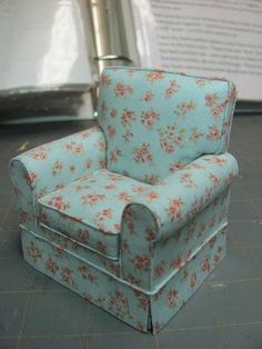 a miniature chair sitting on top of a table next to a metal object that looks like it's made out of fabric