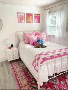 a cat laying on top of a bed in a room with pink and white decor