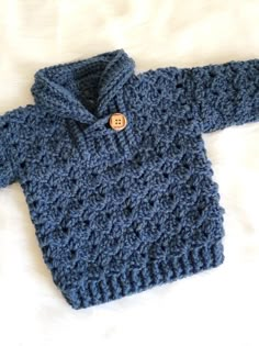 a blue knitted sweater laying on top of a bed