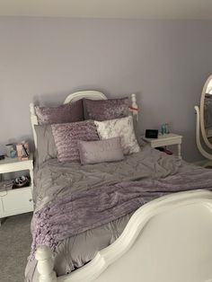 a white bed sitting next to a mirror in a bedroom on top of a carpeted floor