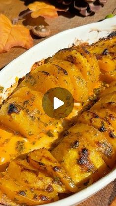 a casserole dish with potatoes and cheese in it on a wooden table next to autumn leaves