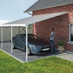 a man standing next to a car in front of a brick building with a white awning