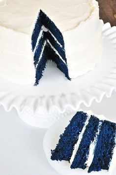 a blue velvet cake with white frosting and two slices cut from it on a plate