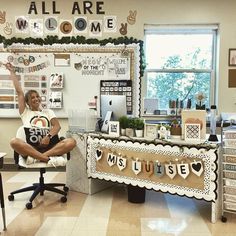 a woman sitting on a chair in front of a desk with an all are welcome banner