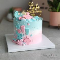 a blue and pink baby shower cake sitting on top of a table