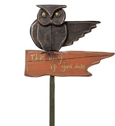 an owl sitting on top of a wooden sign