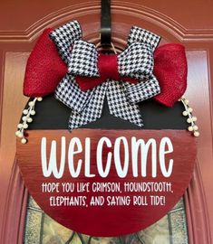 a welcome sign hanging on the front door of a house with red and black bows