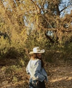 a woman wearing a cowboy hat standing in the woods