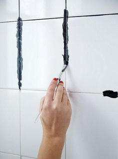 a person is painting the wall with black paint and some white tiling on it