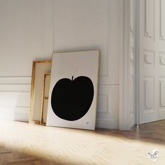 an apple is on the floor next to two framed pictures