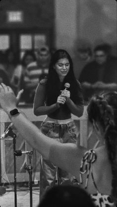 a woman holding a microphone in front of a group of people