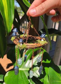 a hand holding a piece of jewelry with blue beads hanging from it