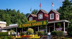 people are standing in front of a restaurant with flags on the roof and trees behind it