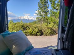 the view from inside an rv looking out at trees, mountains and snow capped peaks